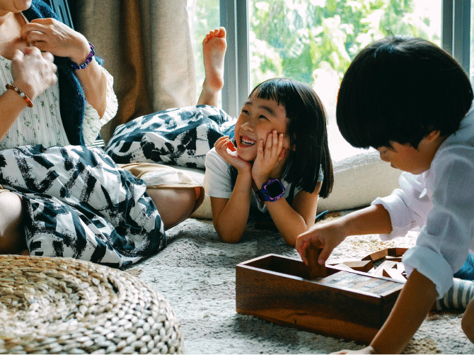 Children playing while on the floor with their grandmother sitting with them